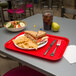 A Carlisle red fast food tray with a sandwich and chips on it.