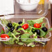 A salad in a Durable Packaging clear hinged plastic take-out container with a fork.