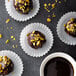 A close up of chocolate covered pistachio balls in a white fluted baking cup.