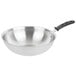 A Vollrath stainless steel stir fry pan with a black TriVent silicone handle.