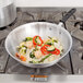 A Vollrath stir fry pan with vegetables and shrimp on a stove.