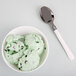 A bowl of mint chocolate chip ice cream with a WNA Comet Reflections Duet stainless steel look plastic spoon.