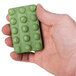 A hand holding a Basic Earth Botanicals green rectangular massage bath soap bar.