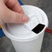A hand opening a white Solo plastic cup lid.
