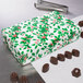 A 2-piece holly patterned candy box filled with chocolate candies.
