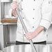 A chef using a Carlisle stainless steel French whisk in a large metal pot.