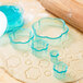 An Ateco plastic cookie cutter set with flower shapes in a clear plastic container with a blue rim.