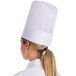 A woman wearing a white Royal Paper disposable chef hat.