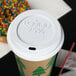 A white Eco-Products hot paper cup lid on a coffee cup with a donut on top.