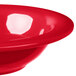 A close up of a red Carlisle melamine fruit bowl with a red rim.