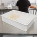 A woman using a white Cambro pizza dough proofing box to store balls of dough.