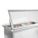 A Beverage-Air stainless steel refrigerated sandwich prep table with glass lids over food containers.