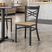 A Lancaster Table & Seating black finish cross back chair with a driftwood seat at a table in a restaurant.