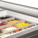 A Beverage-Air stainless steel sandwich prep table with glass lids open to trays of food on a counter.