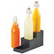 A Cal-Mil 3 step bottle riser holding three bottles of orange juice on a counter.