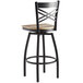 A Lancaster Table & Seating black and wood swivel bar stool with a cross back and driftwood seat.