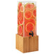 A Cal-Mil bamboo beverage dispenser with watermelon slices in it.