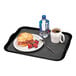 A black Cambro room service tray with a croissant sandwich, a plate of food, and a coffee mug.