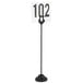 An American Metalcraft black harp table card holder with weighted base holding a table number.