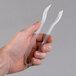 A person holding a pair of clear plastic tongs.