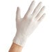 A person's hand wearing a Noble white disposable latex glove.