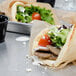 A pita bread filled with Kronos Traditional Gyros Slices, lettuce, tomatoes, and cheese.
