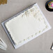A white cake with frosting on a white Enjay quarter sheet cake board.
