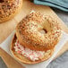 An Original New York Style Everything Bagel with cream cheese and seeds on a wooden board.