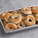 A tray of Original New York Style Blueberry Bagels with blueberries in a metal pan.