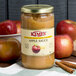 A jar of Kime's cinnamon applesauce on a table with cinnamon sticks.