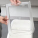 A person holding a clear plastic lid for a Cambro ingredient bin.
