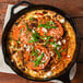 A skillet of fresh liquid whole egg omelet with tomatoes and feta cheese.