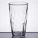 A clear Carlisle polycarbonate tumbler with a swirl design on a table.
