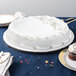 A white cake on a silver round cake drum on a table.