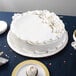 A white cake on an Enjay silver round cake drum on a table.
