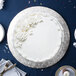 A white cake with white frosting and flowers on a silver Enjay round cake drum on a table.