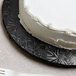A white cake on a black Enjay round cake drum on a plate.