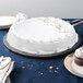 A white cake on a black Enjay round cake drum on a table.
