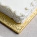 A white cake with frosting on a gold Enjay half sheet cake board.
