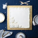 A white cake with white frosting on a gold square cake drum with a white background.