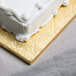 A white cake with frosting on a gold square cake drum.