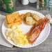 A plate of breakfast food on a white 9" coated paper plate.