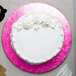 A white cake on a pink Enjay cake drum.