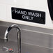 A black and white Thunder Group hand wash only sign on a wall.