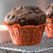 A close-up of a chocolate muffin in a red Enjay baking cup.