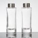 Two clear glass American Metalcraft salt and pepper shakers with silver lids on a table.