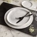 An American Metalcraft faux white marble charger plate with a fork and knife on it.