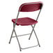 A red Lancaster Table & Seating folding chair with a metal frame.