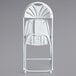 A white plastic Lancaster Table & Seating fan back folding chair.