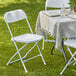 A white Lancaster Table & Seating folding chair on grass.